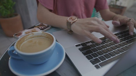 Woman working on laptop she drinks coffee