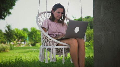 Woman working outdoors on a swing chair.