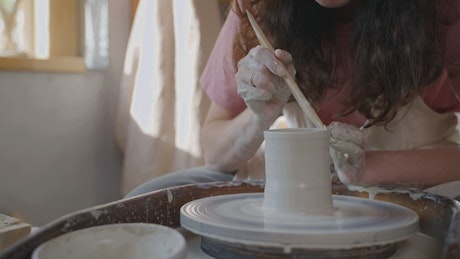 Woman works on the creation of a ceramic flower vase.