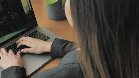 Woman writing on a laptop.