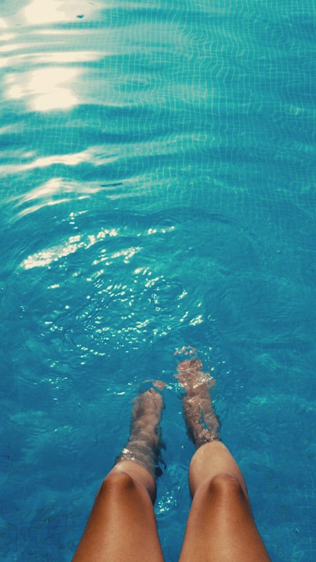 Woman's feet splashing in the pool.