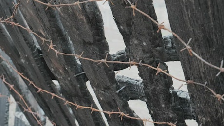 Wooden fence with barbed wire in detail.