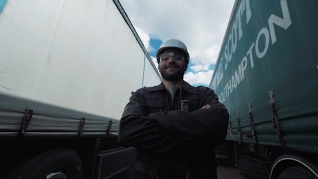 Worker between two freight trucks smiling.