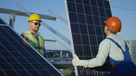 Workers installing a solar panel outdoors