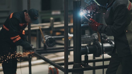 Workers welding heavy metal in a factory.