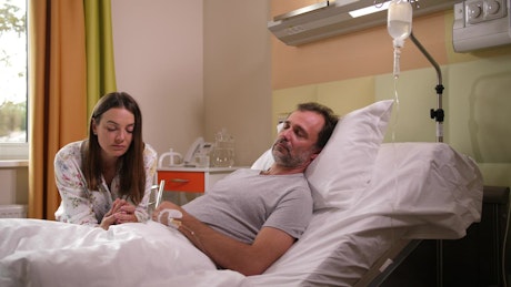 Worried woman by her husband in hospital.