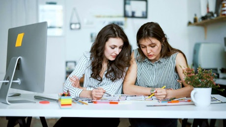 Young architects working on a blueprint with pencils