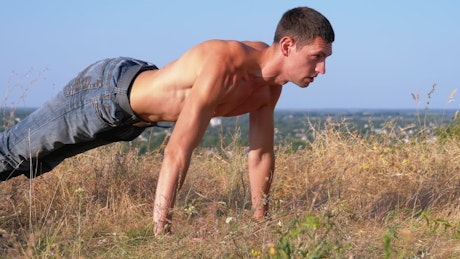 Young athletic man doing push-ups outdoors