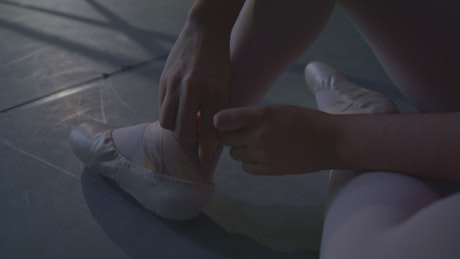 Young ballet dancer putting on her slippers
