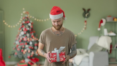 Young bearded tattooed man giving a Christmas gift.