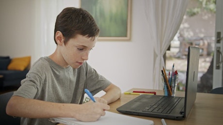 Young boy attending an online lesson during COVID-19 lockdown.