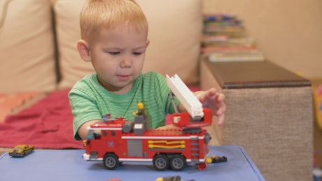 Young boy plating with a toy fire engine.