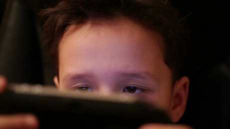 Young boy playing a video game quietly.