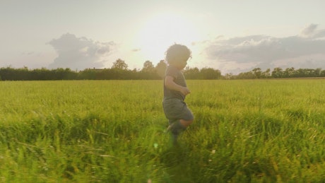 Young boy walking through a field.
