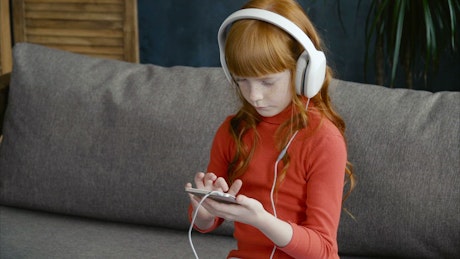 Young child listening to music on a phone