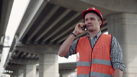 Young construction worker talking on the phone.