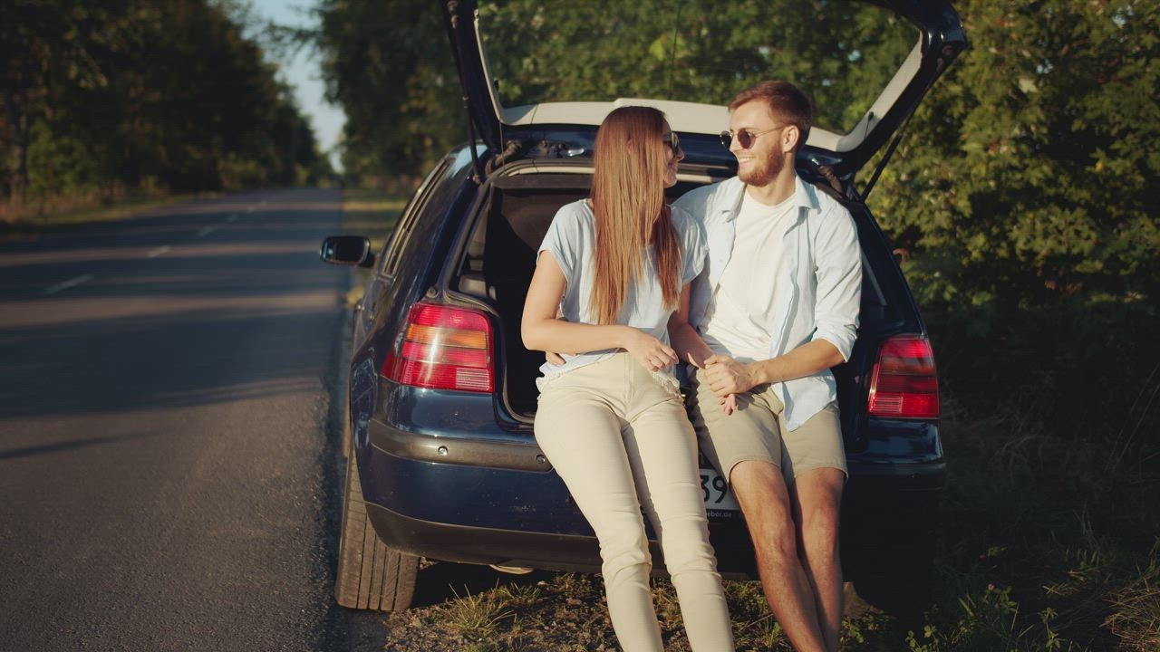 Young couple kiss in back of car in sunny countryside - Free Stock Video