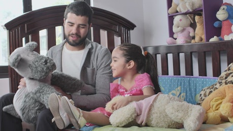 Young dad playing with stuffed animals with his daughter