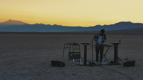 Young DJ mixing music in a desert.