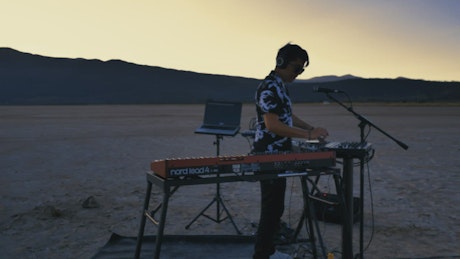 Young DJ mixing music in the desert.