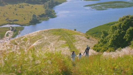 Young family walking down the hill with a lake in the background.