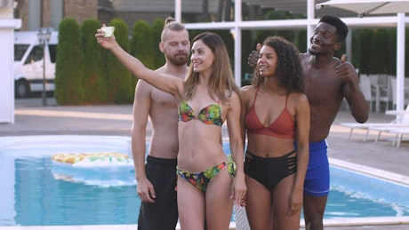 Young friends taking a photo by the pool.