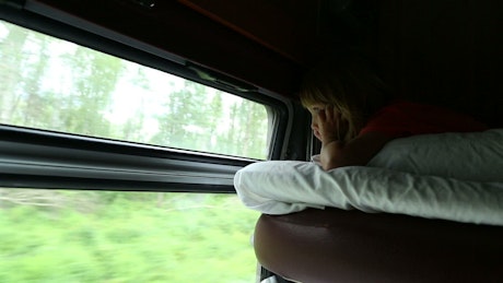 Young girl looking out the train window at nature.