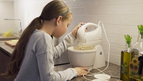 Young girl mixing dough in the kitchen.