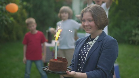 Young girl smiling as she holds her cake at a birthday party.