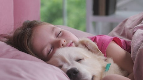 Young girl taking a nap with her puppy.