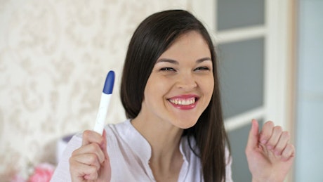 Young happy and excited woman with a pregnancy test.