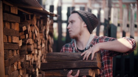 Young lumberjack arranging logs in a pile.