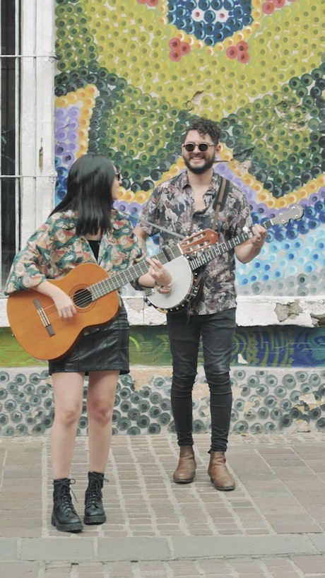 Young man and woman playing music on a colorful street