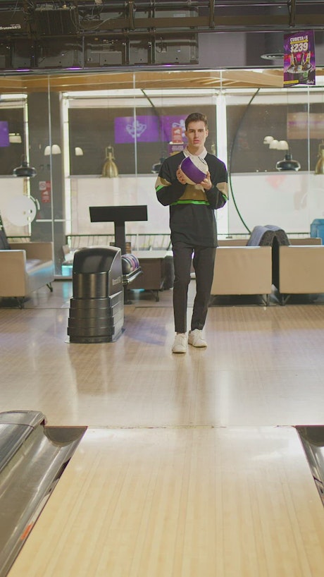 Young man at the bowling center makes a shot.