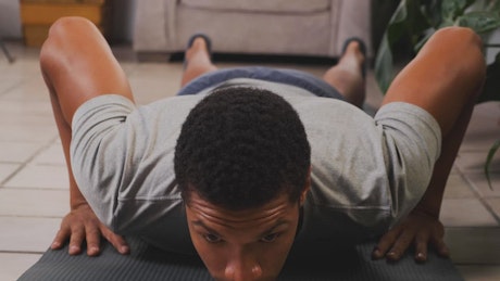 Young man doing push-ups on the floor.