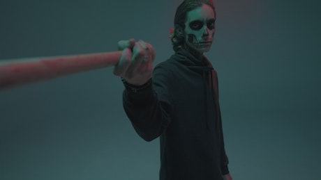 Young man dressed as a skull with a bat.