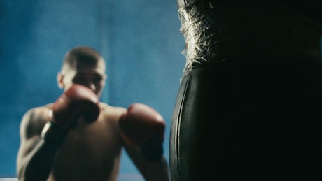 Young man hitting the punching bag at a gym
