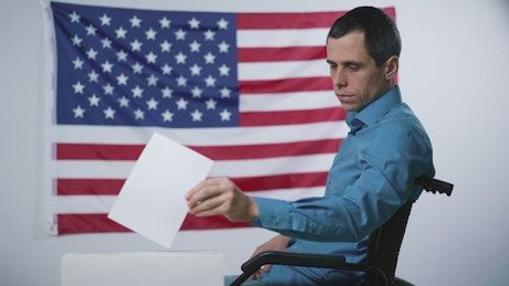 Young man in a wheelchair posting a vote for an election.