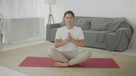 Young man meditating at home, front view.