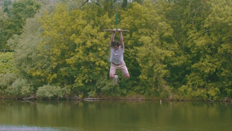 Young man on a lake swing.