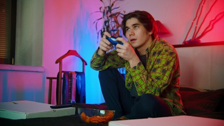 Young man plating video games on the bed