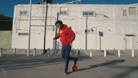 Young man playing soccer in the street.