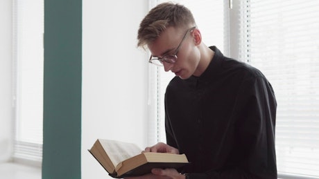 Young man reading a Bible aloud.