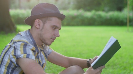 Young man reading a book in the park.