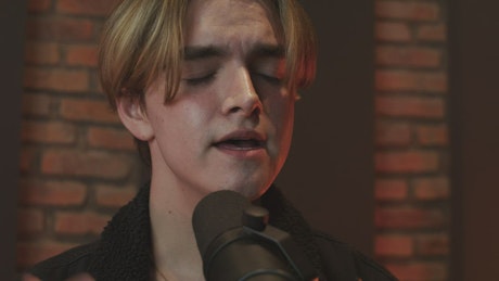 Young man singing into a microphone.