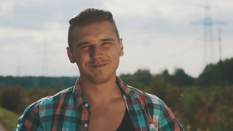Young man with an open shirt smiling.