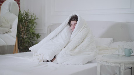 Young man with cold inside the bed.