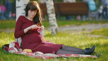 Young pregnant woman knitting.