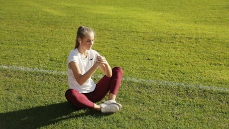 Young runner does stretch routine on track field.