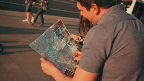Young tourists locating themselves on a map.